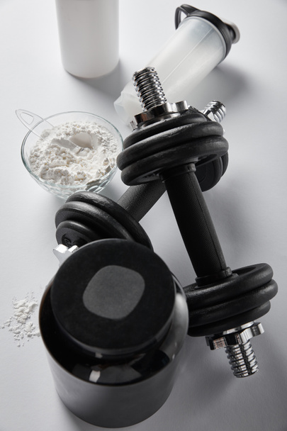 top view of sports bottle near bowl with protein powder and dumbbells on white  - Photo, Image