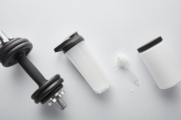 vue du dessus de la cuillère avec des protéines près de haltère et bouteille de sport sur blanc
  - Photo, image