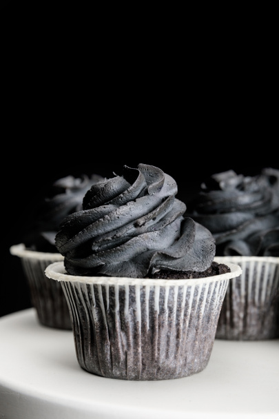 delicious Halloween cupcakes with black cream isolated on black - 写真・画像
