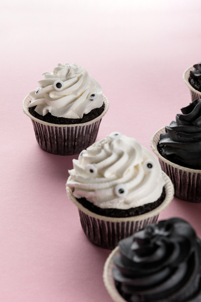 delicious Halloween cupcakes with white and black cream on pink background - Foto, Imagem