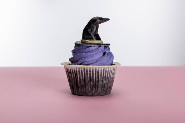 delicious Halloween cupcake with purple cream and hat on pink surface isolated on white - Фото, зображення