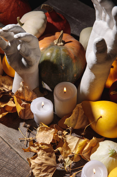 dry foliage, burning candles, ripe pumpkin and decorative hands on wooden rustic table - Photo, Image