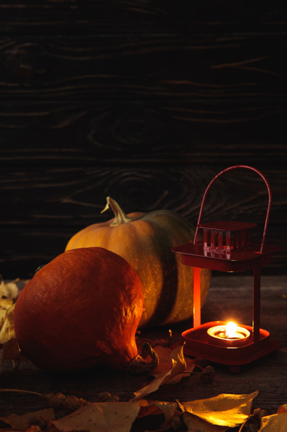 citrouille, feuilles automnales et bougie allumée sur table rustique en bois sur fond noir
 - Photo, image