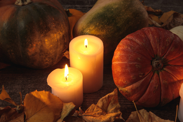 dry foliage, burning candles, ripe pumpkin on wooden rustic table - Foto, afbeelding