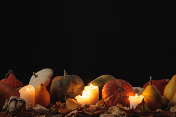 dry foliage, burning candles, ripe pumpkin on wooden rustic table isolated on black - Foto, Bild