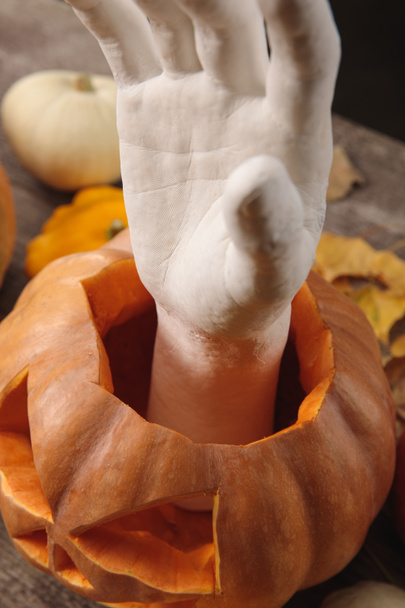 mão decorativa em abóbora de Halloween esculpida em mesa rústica de madeira
 - Foto, Imagem