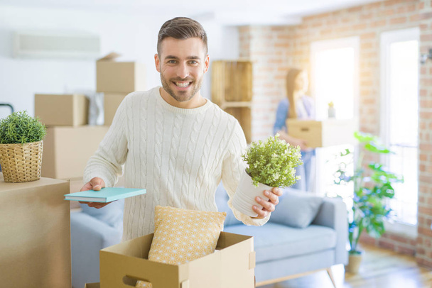Pareja joven mudándose a un nuevo hogar, hombre guapo sonriendo caja de cartón en movimiento
 - Foto, imagen