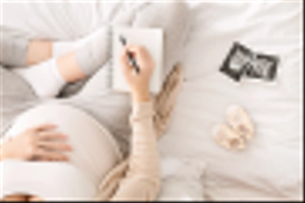 Pregnant woman preparing for labor, sitting on bed with notebook - Foto, Imagem