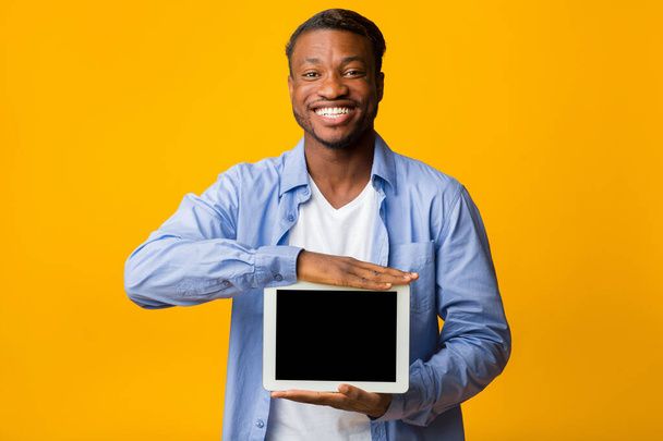 Pozitív Afro Man mutatja üres tabletta képernyő, sárga háttér, Mockup - Fotó, kép