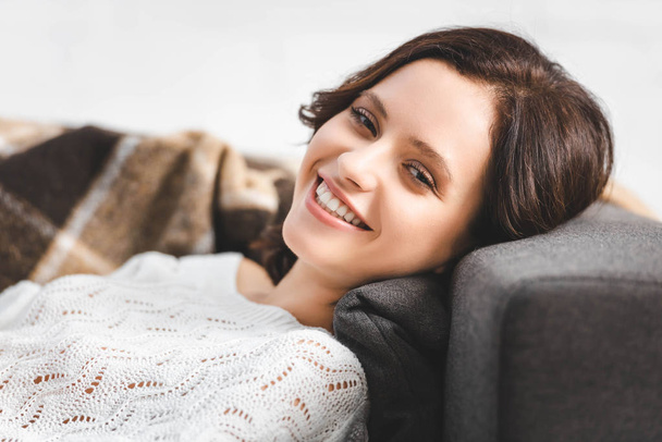 beautiful happy girl lying on sofa and looking at camera - Zdjęcie, obraz