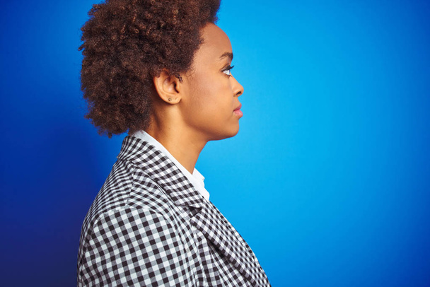 Afro-amerikai üzleti végrehajtó nő több mint elszigetelt kék háttér látszó-hoz oldal, Relax profil pózol természetes arcát magabiztos mosoly. - Fotó, kép