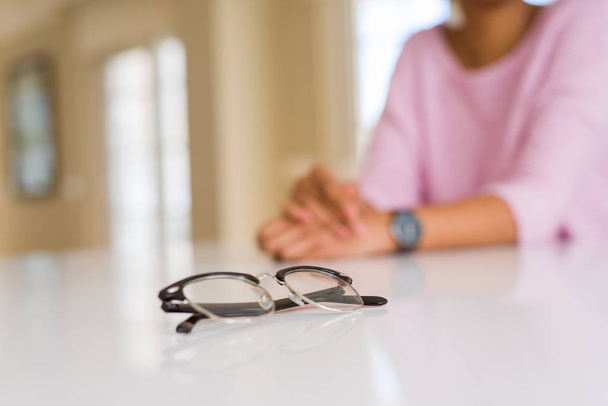 Primo piano di occhiali da vista su tavolo bianco con giovane donna sullo sfondo
 - Foto, immagini