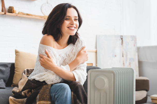 beautiful cheerful woman in cold room with heater - Foto, Imagen