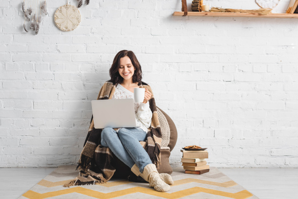 όμορφη ευτυχισμένη γυναίκα με μπισκότα και καφέ χρησιμοποιώντας φορητό υπολογιστή - Φωτογραφία, εικόνα