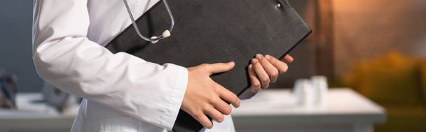 cropped view of doctor in white coat holding clipboard during night shift - Photo, Image