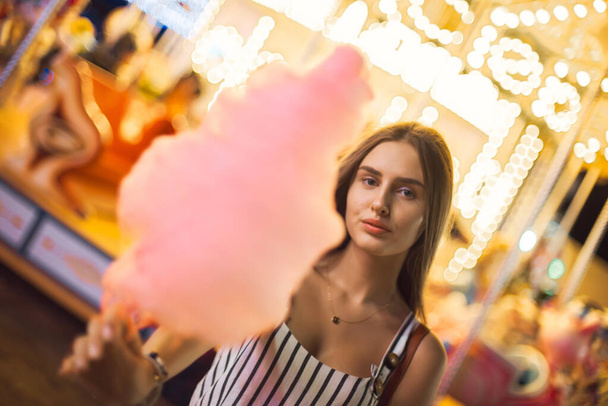 Pretty young woman against the background of magical bright carousel lights. - Foto, imagen