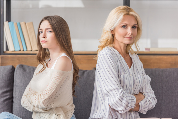 offended mother and daughter sitting back to back while looking at camera - Photo, Image