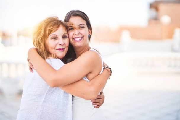 Schöne Mutter und Tochter umarmen sich auf der Terrasse mit glücklichem Gesicht - Foto, Bild