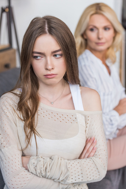 selective focus of offended girl sitting with crossed arms near serious mother - Photo, Image