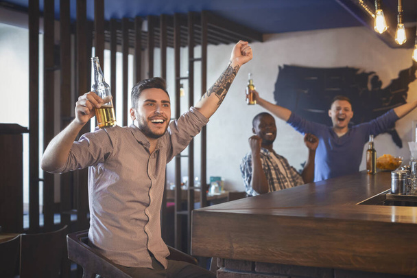 Szczęśliwi fani piłki nożnej świętują zwycięstwo, oglądając mecz w barze - Zdjęcie, obraz