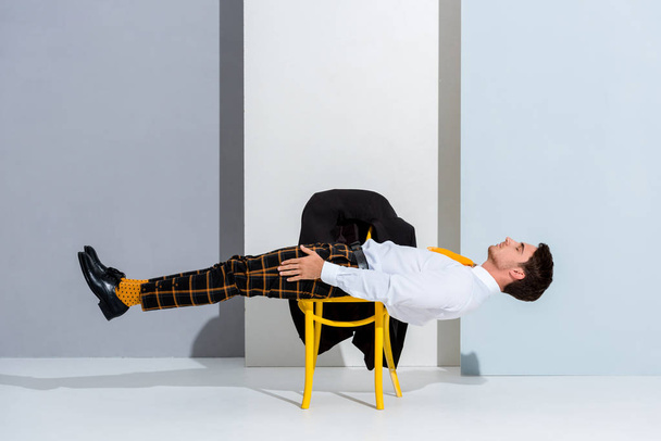 man posing while lying on yellow chair on white and grey  - Zdjęcie, obraz