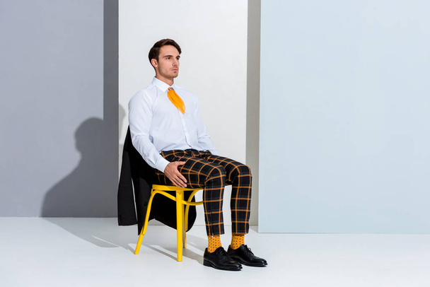 young man sitting on yellow chair on white and grey  - Photo, Image