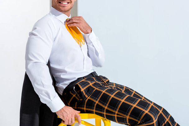 обрізаний вид щасливого чоловіка в картатих штанах, що сидять на білому
  - Фото, зображення