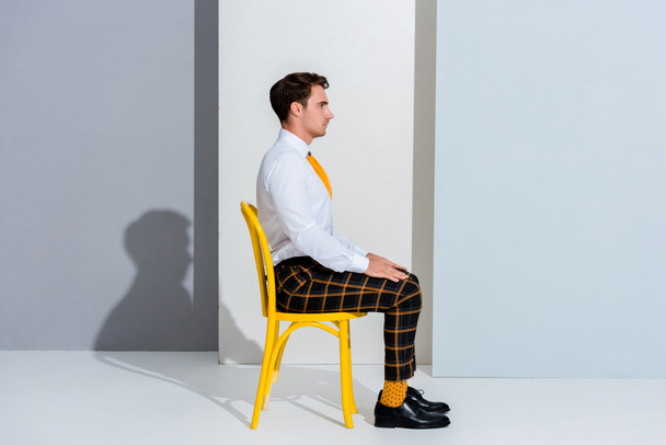side view of man in checkered trousers sitting on white and grey  - Fotografie, Obrázek