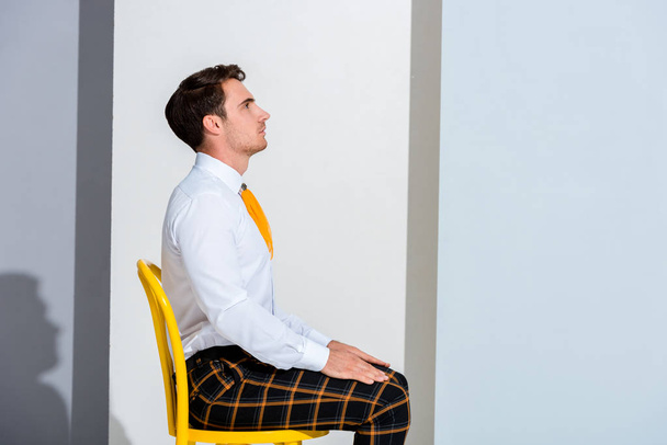 side view of man in plaid trousers sitting on white and grey  - Photo, Image