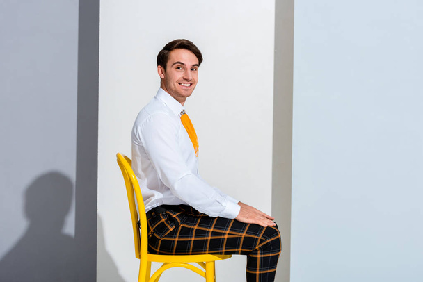 hombre alegre en pantalones a cuadros sentados en blanco y gris
 - Foto, Imagen