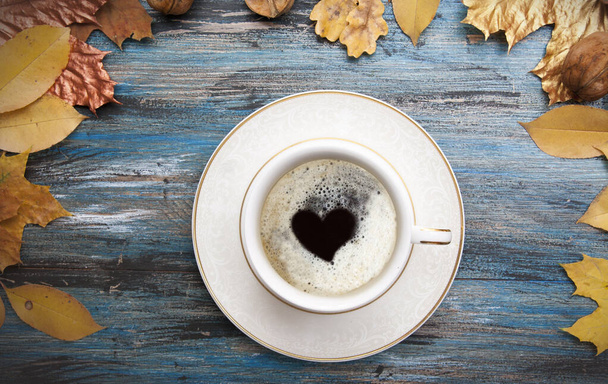 Aménagement d'automne, une tasse de café avec un cœur à l'intérieur de la mousse, feuilles orange et dorées sur fond de bois bleu vintage
 - Photo, image