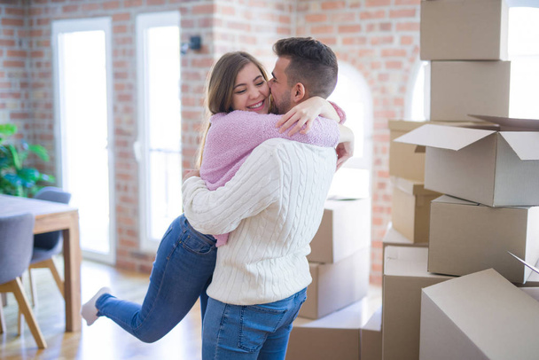 Young beautiful couple hugging in love celebrating very happy moving to new apartment - Photo, Image