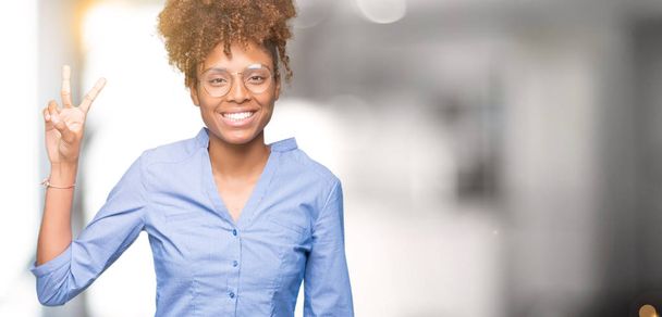 Mooie jonge Afro-Amerikaanse zakenvrouw over geïsoleerde achtergrond weergeven en met de vingers omhoog nummer twee terwijl lacht zelfverzekerd en blij. - Foto, afbeelding