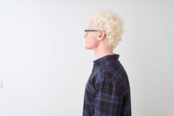 Молодий альбіно блондин в повсякденній сорочці і окулярах над ізольованим білим тлом, дивлячись в бік, розслабляє профільну позу з природним обличчям з впевненою посмішкою
. - Фото, зображення