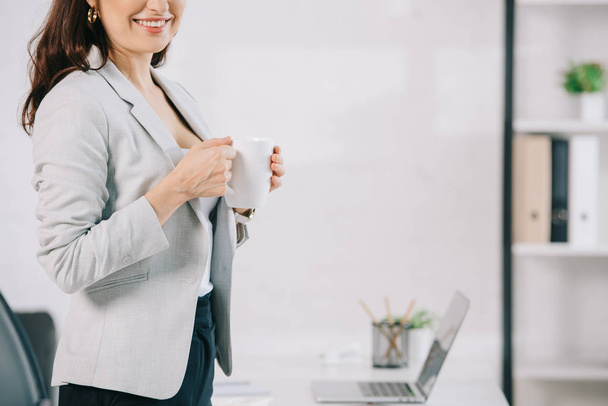cropped view of elegant secretary holding coffee cup in office - Photo, Image