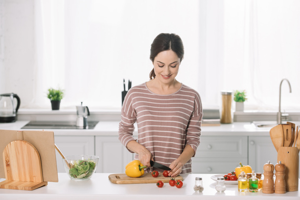 attractive young woman cutting fresh vegetables on chopping board  - Fotó, kép