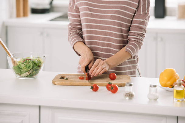 cropped view of woman cutting cheery tomatoes on chopping board - Фото, изображение