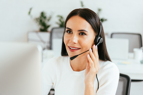 selective focus of attractive broker touching headset while working in call center  - Фото, изображение