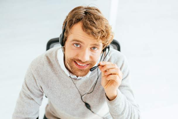 overhead view of cheerful bearded broker looking at camera in office  - Foto, Bild
