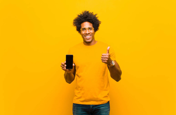 young african american man with a smart phone against orange bac - Fotoğraf, Görsel