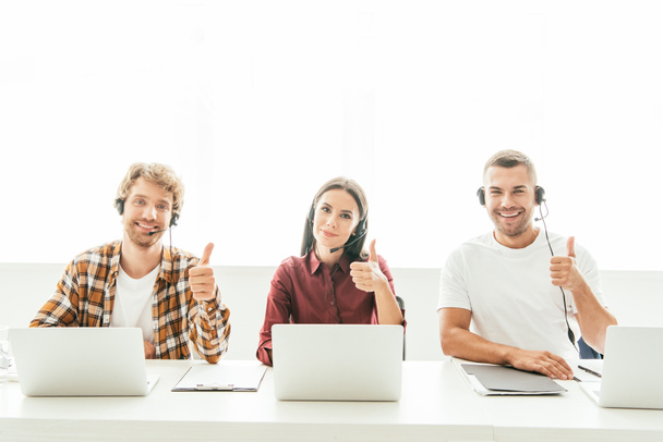 happy brokers in headsets showing thumbs up in call center  - Фото, зображення