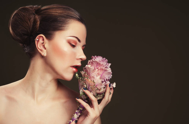 beautiful young woman with makeup in gentle colors holds a big pink flower, beauty concept - Фото, изображение