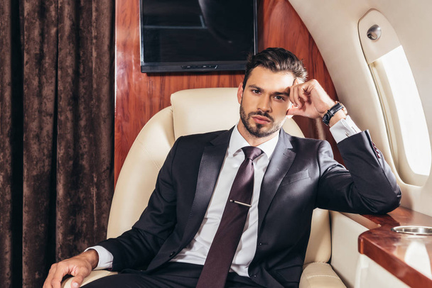 pensive businessman in suit looking at camera in private plane  - Foto, Imagem