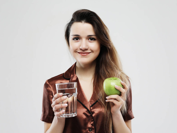 lifestyle, health and people concept - young woman wearing pajamas holding water glass - Foto, Imagen
