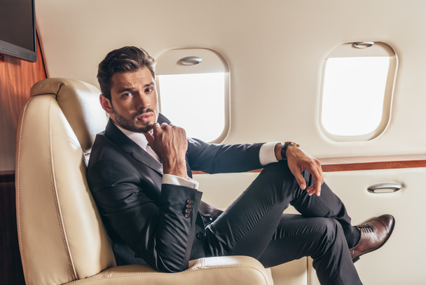bel homme d'affaires en costume regardant la caméra dans un avion privé
  - Photo, image
