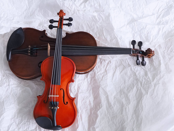 The smaller violin put on bigger one,show detail and different size of acoustic instrument,on grunge surface background,blurry light around - Foto, imagen