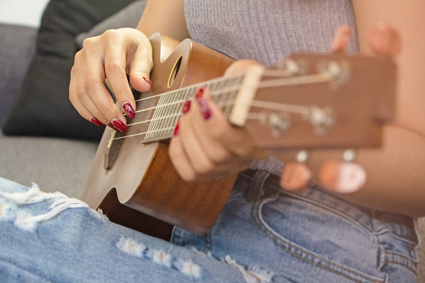 Zbliżenie prawa ręka kobiety gra ukulele, rozmyta lewa ręka, pokazać, jak grać na instrumencie akustycznym - Zdjęcie, obraz