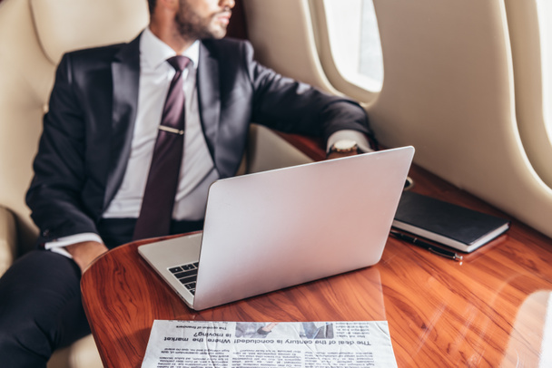 vue recadrée de l'homme d'affaires en costume et ordinateur portable sur la table en avion privé
  - Photo, image