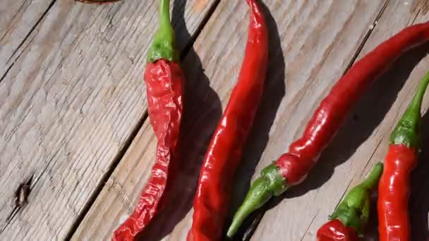 červené chilli papričky na dřevěný stůl - Záběry, video