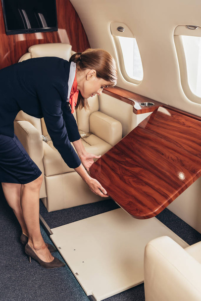 стюардесса в форме держит деревянный табак в частном самолете
  - Фото, изображение